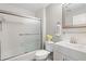 Well-lit bathroom with a frosted glass enclosed shower/tub combination, toilet, and vanity with mirror at 121 Tidy Island Blvd, Bradenton, FL 34210