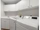 Bright laundry room with white cabinets, countertop space, and modern, white, front-load washer and dryer at 121 Tidy Island Blvd, Bradenton, FL 34210