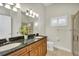 Bathroom featuring double sinks, granite countertops, a window, and a shower with glass doors at 12622 Safe Harbour Dr, Cortez, FL 34215