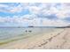 Picturesque beach scene with calm waters, a pier, and a sandy shoreline under a partly cloudy sky at 12622 Safe Harbour Dr, Cortez, FL 34215