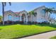 Stunning home with a well-manicured lawn, an arched entrance, and tropical palm trees at 12622 Safe Harbour Dr, Cortez, FL 34215