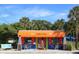 Quaint grill with an orange awning, outdoor seating, and tropical greenery in a beachside setting at 12622 Safe Harbour Dr, Cortez, FL 34215