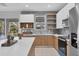 Modern kitchen featuring gray backsplash, light wood cabinets, white countertops, and stainless steel appliances at 1313 Kacerik St, North Port, FL 34288