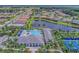 Aerial view of a community clubhouse, pool, tennis courts, and surrounding homes with lush landscaping and a lake at 13630 Deep Blue Pl, Bradenton, FL 34211