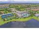 Expansive aerial shot showcasing the community pool, tennis courts, and clubhouse set amidst a scenic residential landscape at 13630 Deep Blue Pl, Bradenton, FL 34211
