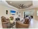 Cozy living room featuring a tray ceiling, fan, comfortable seating, and an entertainment center at 13630 Deep Blue Pl, Bradenton, FL 34211