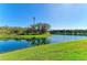 Lush green lawn leads to a tranquil pond with clear blue sky above on a sunny day at 13630 Deep Blue Pl, Bradenton, FL 34211