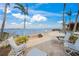 Scenic backyard featuring a stone patio, lounge chairs, and a picturesque waterfront view with palm trees at 204 N Washington Dr, Sarasota, FL 34236