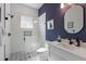 Modern bathroom with walk-in shower, white tile, geometric tile floor, and navy accent wall at 211 81St St # B, Holmes Beach, FL 34217