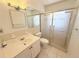 Bathroom features a vanity with sink, mirror, decorative lights, toilet, and shower with glass doors at 3035 Pershing Ave, Sarasota, FL 34234
