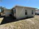 This home features a light gray stucco exterior with well-maintained gutters and two windows, plus a small palm tree in the yard at 3035 Pershing Ave, Sarasota, FL 34234
