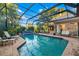 Beautiful screened-in pool oasis features tropical plants, brick patio, lounge chairs, and outdoor dining at 4468 White Egret Ln, Sarasota, FL 34238