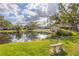 Scenic backyard view with a pond, bench, mature trees, and community pool area at 4527 La Jolla Dr, Bradenton, FL 34210