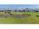 Exterior view of a condo building with lush green lawn, pond, and manicured landscaping at 4734 Independence Dr # 4734, Bradenton, FL 34210