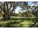 Expansive green space with mature trees providing shade and a walking path in the background at 4920 Kestral Park Cir # 11, Sarasota, FL 34231