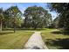 Scenic view of lush green property featuring mature trees and a gravel walking path that forks in the middle of the yard at 4920 Kestral Park Cir # 11, Sarasota, FL 34231