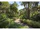 Lush landscaped walkway with verdant foliage, tropical plants, brick path, and mature, shaded trees at 4920 Kestral Park Cir # 11, Sarasota, FL 34231