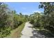 Gravel walking path surrounded by greenery leading to a wooded area at 4920 Kestral Park Cir # 11, Sarasota, FL 34231