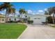 Charming light blue home with lush green lawn, palm trees, and a two-car garage in a tropical setting at 511 77Th St, Holmes Beach, FL 34217