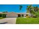 Charming single-story home showcasing lush tropical landscaping, a well-maintained lawn, and an attached two-car garage at 526 Bird Key Dr, Sarasota, FL 34236