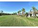 Charming backyard view featuring a screened lanai, lush grass, and swaying palm trees at 5283 Chase Oaks Dr, Sarasota, FL 34241