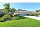 Charming home featuring a well-manicured lawn, colorful flowerbeds, and a convenient two-car garage at 5283 Chase Oaks Dr, Sarasota, FL 34241