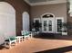 Inviting entryway with white rocking chairs, a brick facade, and glass double doors, creating a welcoming ambiance at 5712 Cottonwood St, Bradenton, FL 34203