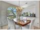 Dining area with large window, chandelier, light wood floors, and elegant decor at 5729 Garden Lakes Palm, Bradenton, FL 34203