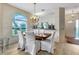 Dining area featuring a chandelier, large window, light wood floors, and a dining table with white chairs at 5729 Garden Lakes Palm, Bradenton, FL 34203