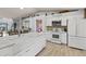 Modern kitchen with stainless appliances, white cabinetry, a center island, and wood-look tile flooring at 604 68Th Avenue W Dr, Bradenton, FL 34207