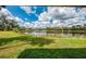 Serene view from under a covered structure towards a lake with lush green grass and mature trees at 7123 Heron Dr, Sarasota, FL 34243