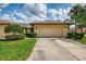 Single-story home featuring a two-car garage, well-maintained lawn, and manicured shrubbery at 7123 Heron Dr, Sarasota, FL 34243