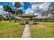 Picturesque lakeside gazebo with seating and lovely views on a well manicured lawn and blue sky at 7123 Heron Dr, Sarasota, FL 34243