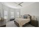 Cozy bedroom featuring a ceiling fan, plush bedding, neutral decor, and ample natural light from several windows at 9028 Sunray Cv, Parrish, FL 34219