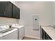 Laundry room with black cabinets, white washer and dryer, and light wood-look floors at 9028 Sunray Cv, Parrish, FL 34219