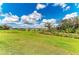 Lush green backyard leading to a tranquil pond and distant houses under a bright sky at 9339 Ballaster Pointe Loop, Parrish, FL 34219