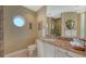 The bathroom has a marble vanity top, round window, and tiled shower with glass doors at 990 Blvd Of The Arts # 1203, Sarasota, FL 34236