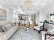 Bright living room features a modern chandelier, comfortable seating, and an open floor plan that flows into the kitchen at 10520 Boardwalk Loop # 205, Lakewood Ranch, FL 34202