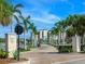 Scenic street view with palm-lined drive leading to waterfront condos; a picturesque entrance to luxury living at 10520 Boardwalk Loop # 205, Lakewood Ranch, FL 34202