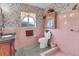 Vintage bathroom with pink tile, floral wallpaper, dark granite sink, and shower at 1103 Palma Sola Blvd, Bradenton, FL 34209