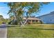 Charming single-story home with a well-kept lawn and mature tree, featuring a classic design under a bright blue sky at 1103 Palma Sola Blvd, Bradenton, FL 34209