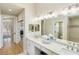 Bright bathroom with double sinks, white cabinetry, granite counters, and decorative mirror at 121 N Boulevard Of Presidents, Sarasota, FL 34236