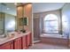 Bathroom featuring dual sinks, vanity cabinets, and a separate shower and arched window over the tub at 12286 23Rd E St, Parrish, FL 34219