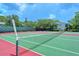 Outdoor tennis courts with red and green surfaces, tall fences, and green landscaping at 1601 Pelican Point Dr # 212, Sarasota, FL 34231