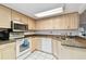 Well-lit kitchen featuring neutral cabinets, dark countertops, tile floors and stainless steel appliances at 2774 71St St Ct W # 2101, Bradenton, FL 34209