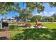 Outdoor picnic area with several red picnic tables on concrete pads, with surrounding green grass and mature trees at 2774 71St St Ct W # 2101, Bradenton, FL 34209