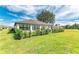 Home's exterior view with lush lawn, well-maintained hedges, and cozy outdoor patio seating at 279 Park Forest Blvd, Englewood, FL 34223