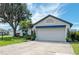 Garage view of a single-story home featuring an attached garage, a blue awning, and mature landscaping at 279 Park Forest Blvd, Englewood, FL 34223