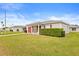 Single-story home with a red garage door, tidy landscaping, and a cozy front porch seating area at 29353 Princeville Dr, San Antonio, FL 33576