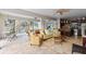 Open-concept living room with travertine floors, wicker furniture, ceiling fans, and a partial kitchen at 310 79Th Nw St, Bradenton, FL 34209